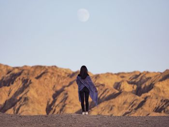 Rear view of woman standing on desert