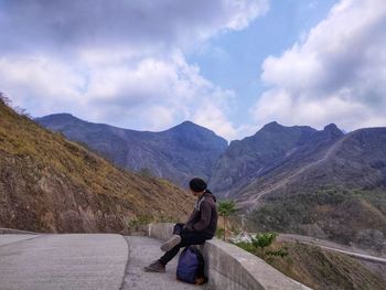 Rear view of man looking at mountains against sky