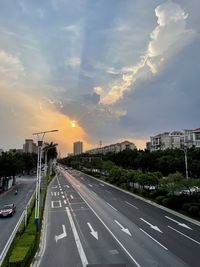 Road by street against sky during sunset