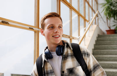 Portrait of young woman standing against railing