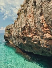 Rock formation in sea against sky