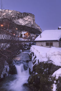 A view of a river and a house in selva di val gardena ski resort, italy at dusk during winter time