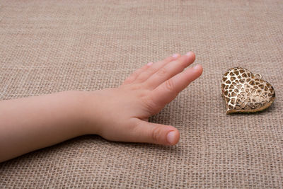 Cropped hand reaching for golden heart shape on table