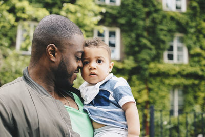 Close-up of father embracing son against building