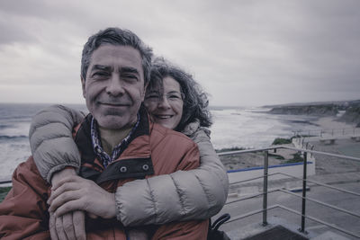 Portrait of happy couple on beach against sky