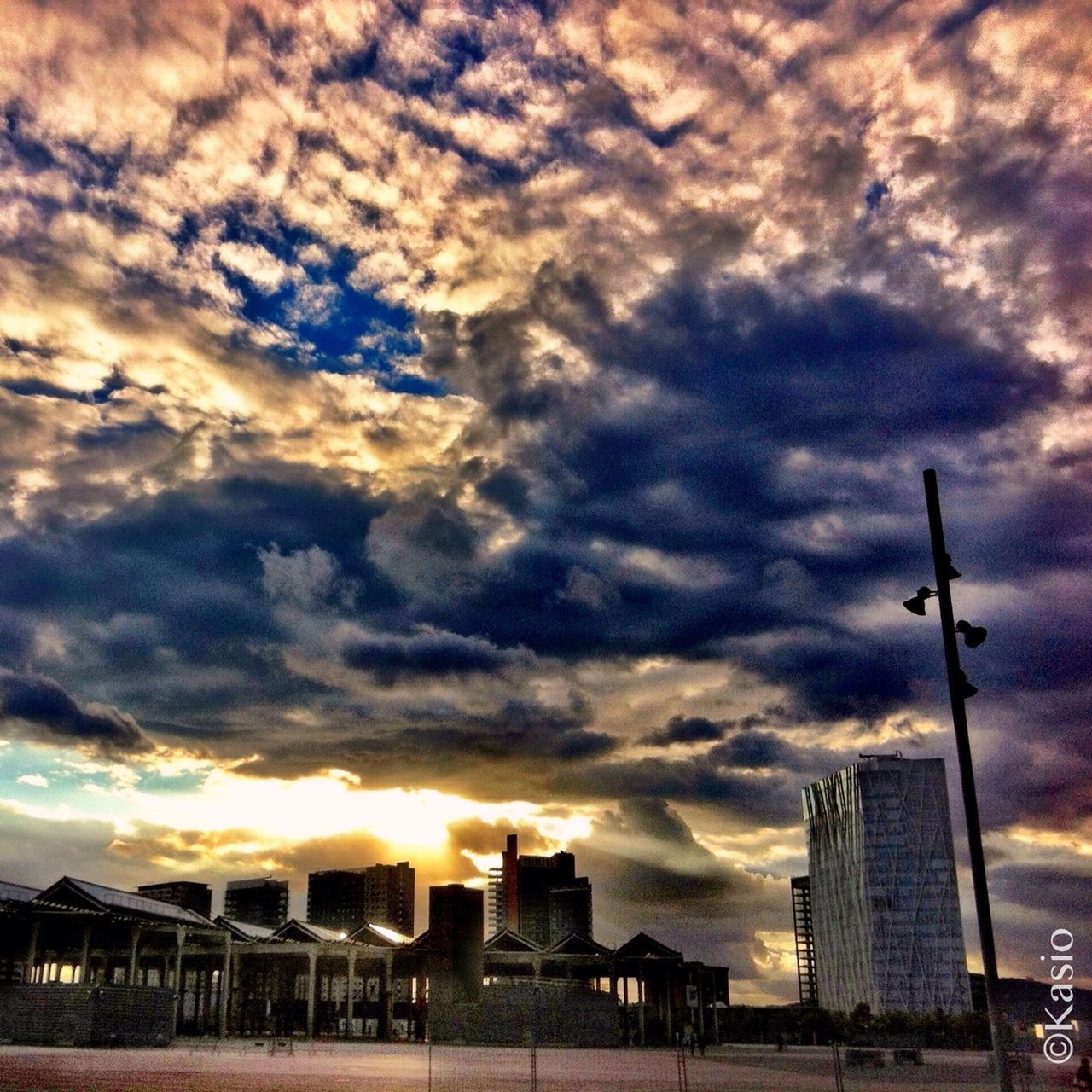 building exterior, architecture, sky, cloud - sky, built structure, sunset, cloudy, city, weather, cloud, cityscape, crane - construction machinery, low angle view, modern, street light, skyscraper, overcast, building, development, silhouette