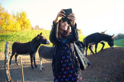 Girl gets a selfie with donkeys in the countryside