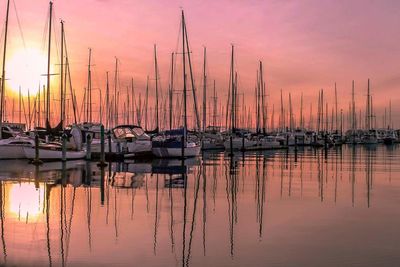 Sailboats moored on lake against sky during sunset