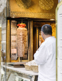 Rear view of man standing by doner kebab at market