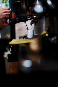 Cropped hands pouring coffee in cup at cafe