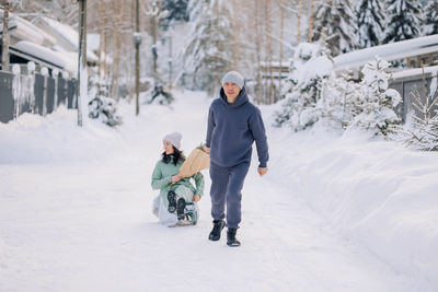 Smiling man giving sledding ride to woman. love and leisure concept.