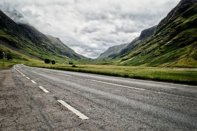 Road by mountains against sky