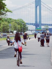 Rear view of women walking on road by suspension bridge