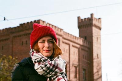 Portrait of young woman standing against castle