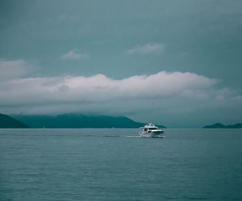 Yacht in sea against cloudy sky