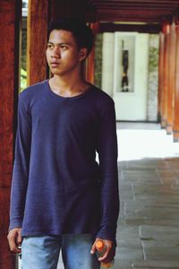 Man looking away while standing in corridor