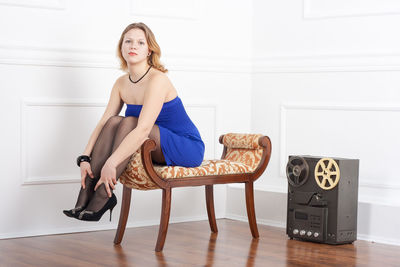 Portrait of sensuous young woman sitting on footstool at home