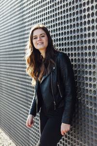 Portrait of young woman in leather jacket standing outdoors