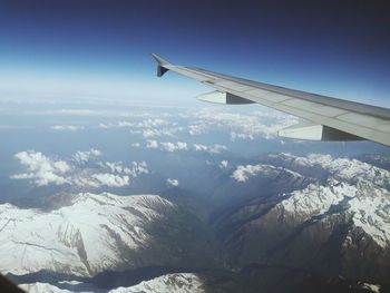 Aerial view of snow covered landscape against blue sky