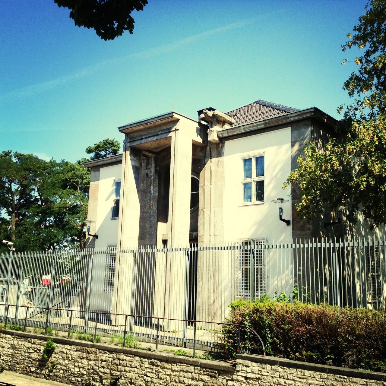 building exterior, architecture, built structure, tree, clear sky, house, sunlight, plant, blue, day, sky, residential structure, outdoors, growth, no people, facade, residential building, low angle view, gate, shadow