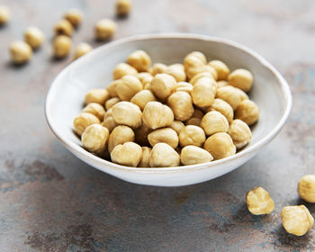 Peeled hazelnuts in a bowl on grey concrete background