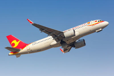 Low angle view of airplane flying against clear blue sky