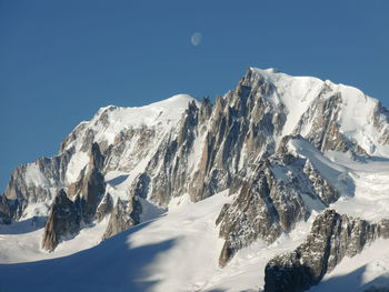 Scenic view of snow covered mountains against clear blue sky