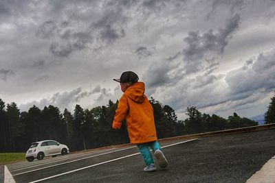 Rear view of boy on car against sky