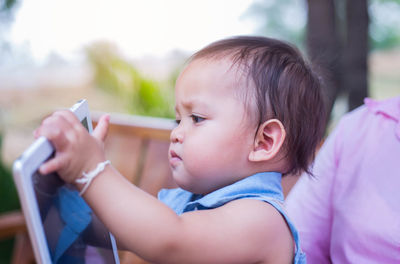 Close-up portrait of cute baby girl holding camera