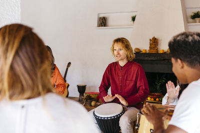 Man playing bongo by friends in classroom