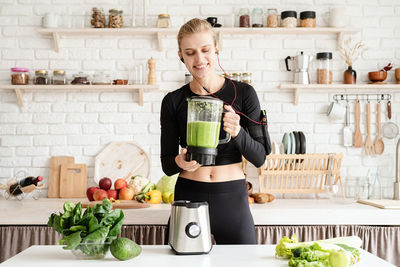 Young woman listening music while preparing food in kitchen at home