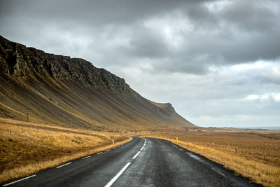 Road leading towards mountains against sky