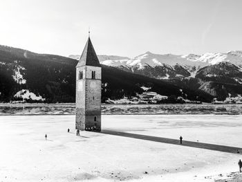 Building by snowcapped mountains against sky