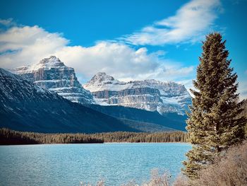 Scenic view of lake by snowcapped mountains against sky