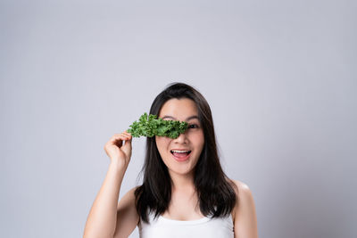 Portrait of young woman holding food against white background