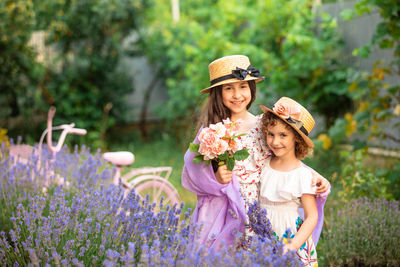 Portrait of smiling young woman standing by flowering plants