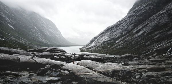 Scenic view of people on rock formation against fjord