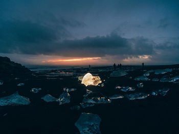 Rocks by sea against sky during sunset