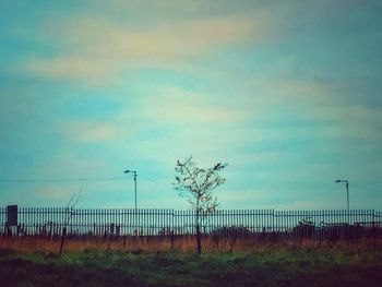 Fence on field against sky during sunset