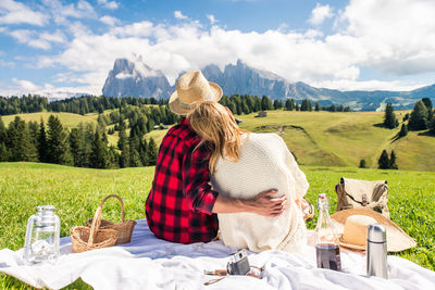 Rear view of couple sitting on mountain against sky