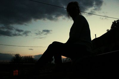 Low angle view of silhouette man sitting against sky during sunset