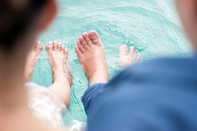 Low section of couple relaxing at edge of swimming pool