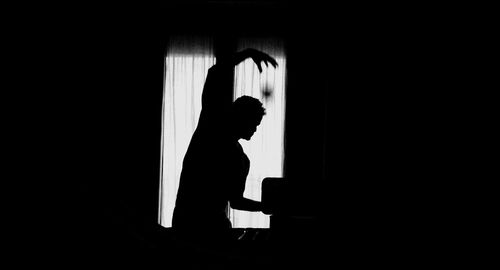 Silhouette man gesturing in darkroom at home