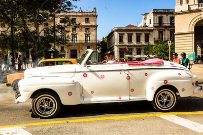 Vintage car on street against buildings in city