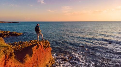 Man looking at sea against sky during sunset