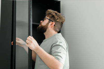 Side view of young man looking through window