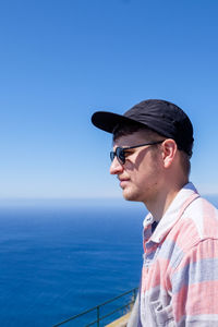 Portrait of young man wearing sunglasses against sea