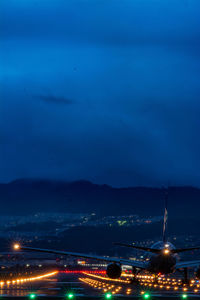 Illuminated city by sea against sky at night