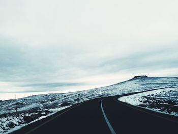 Road by snowcapped mountain against sky