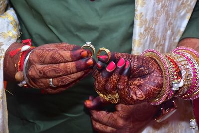 Midsection of couple holding rings in wedding ceremony